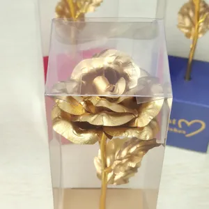 Gold foil artificial rose flower in clear gift box, detail view of romantic holiday gift.