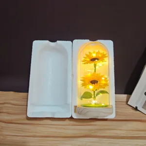 Close-up detail of sunflower glass dome night light with warm LED fairy lights, wooden base.