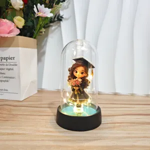Detail view of the graduation LED glass dome ornament with cartoon figurine and warm lights.