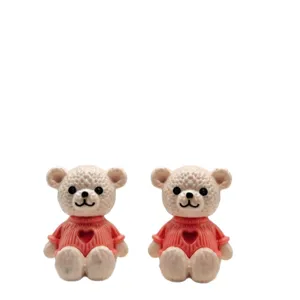 Linda estatuilla en miniatura de oso de peluche de plástico con suéter de corazón rosa.