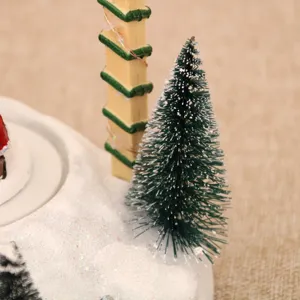 Dettaglio primo piano di decorazione natalizia con scena di neve, mini albero e base innevata.