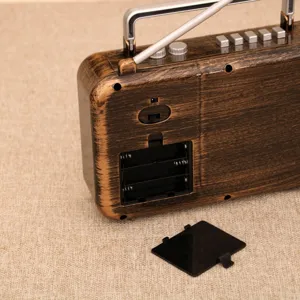 Retro wood grain radio detail view showcasing the open battery compartment and top control buttons.