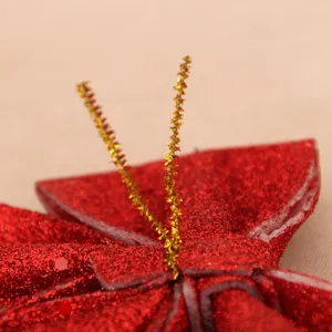 Close-up detail shot of red glitter Christmas bow decoration with gold metallic twist ties.