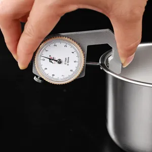 Detailed view of measuring stainless steel bowl rim thickness with precision mechanical dial gauge.