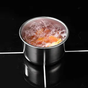 Stainless steel steaming bowl detail view showing boiling food inside on a cooktop surface.