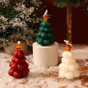 Detailansicht festlicher Weihnachtsbaum Duftkerzen in gruen und rot mit winterlicher Deko.