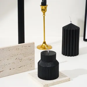 Vue détaillée de bougies parfumées noires cannelées présentées sur de la pierre.