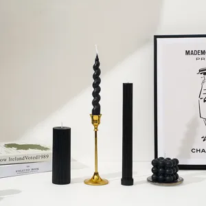 Vue détaillée de bougies parfumées noires avec bougeoir doré, décor minimaliste chic.