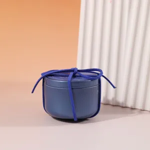Candela profumata in latta blu rotonda con nastro in camoscio, dettaglio decoro casa.