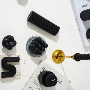 Vue détaillée d'une collection de bougies parfumées noires aux formes géométriques et rainurées.