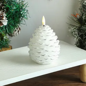 Gros plan sur la bougie LED en forme de pomme de pin blanche avec bord argenté pour déco de Noël.