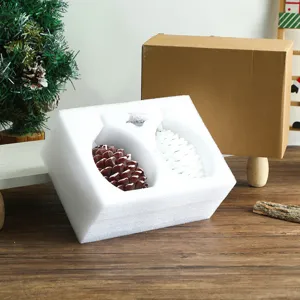 Vue détaillée de bougies LED en pomme de pin avec emballage en mousse sur fond de table en bois.