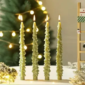Detailed view of green Christmas tree taper candles burning warmly for holiday decor.