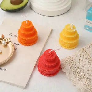 Detailed close-up of colorful tiered cake scented soy wax candles styled for table decor.