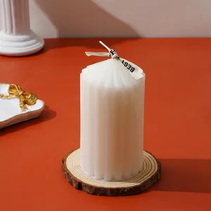 Primer plano de la vela aromática acanalada blanca con cinta decorativa sobre base de madera.