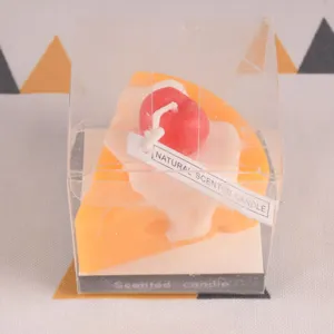 Closeup of a cute slice cake scented candle in transparent box with natural fragrance tag.