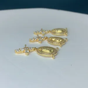 Nahaufnahme Detail von vergoldeten Kreuz und ovalen Porträt Anhänger mit Zirkonia Steinen.