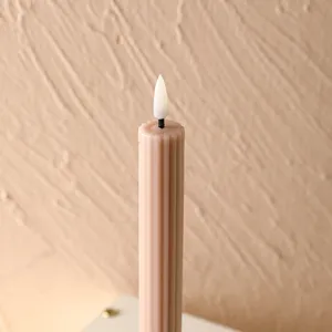 Gros plan détaillé d'une bougie LED rose striée dotée d'une flamme artificielle réaliste.