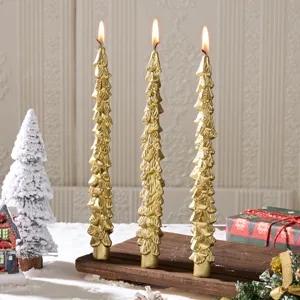Gold Christmas tree pillar candles set on wooden base with festive holiday decor.