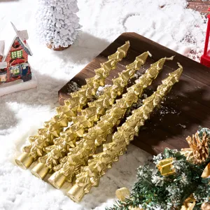 Detailed view of gold Christmas tree shaped taper candles displayed on a rustic snowy wooden board.