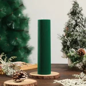 Close-up detail of a dark green ribbed pillar candle set on a wooden base for cozy decor.