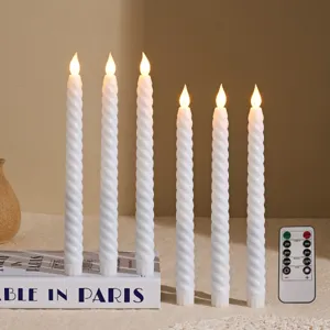 Close-up of elegant white twisted LED taper candles with remote control on a decorative book.