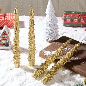 Detailed view of golden Christmas tree shaped taper candles in a festive snowy setting prop.