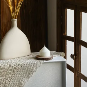 Close-up shot of a white striped cone pillar scented candle styled on wooden slice coaster.