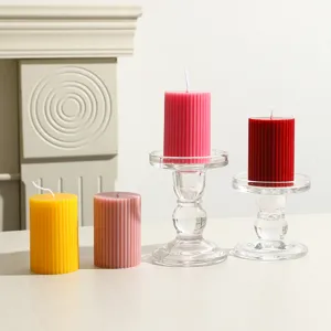 Detailaufnahme von bunten gestreiften Stumpenkerzen mit Glas-Kerzenhaltern, Wohndekoration.