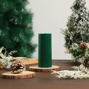 Detailed view of the dark green ribbed cylindrical soy wax candle placed on a rustic wood slice.
