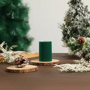 Detail view of the green striped cylindrical soy wax scented candle with holiday decor setup.