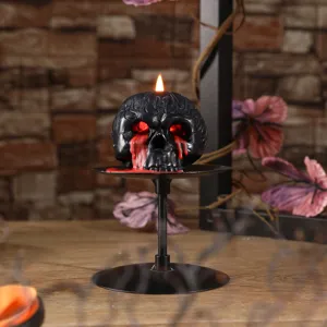 Gothic skull candle for Halloween decoration, black wax with red dripping blood and eyes.