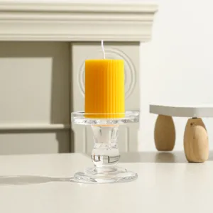Gelbe gerippte Stumpenkerze mit klarem Glashalter, ideal für Heimdekoration und Geschenke.