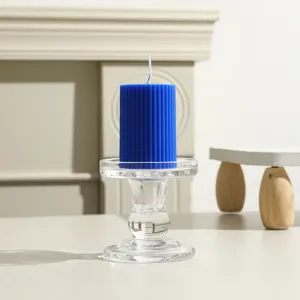 Nahaufnahme Detailansicht einer blauen gerippten Stumpenkerze auf einem klaren Kerzenhalter.