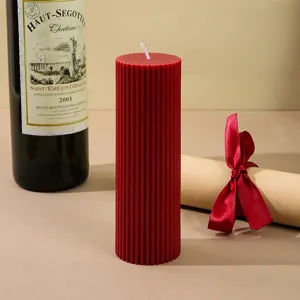 Close-up of an elegant red ribbed pillar scented candle displayed in a warm styled setting.