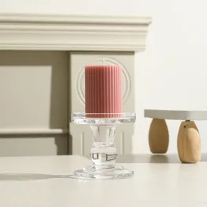 Detailaufnahme einer rosa gerillten Stumpenkerze auf einem klaren Kerzenhalter aus Glas.