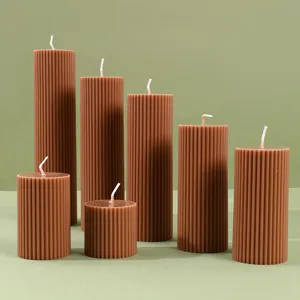 Vela aromática cilíndrica marrón, diseño columna romana, detalle decoración cera soja.