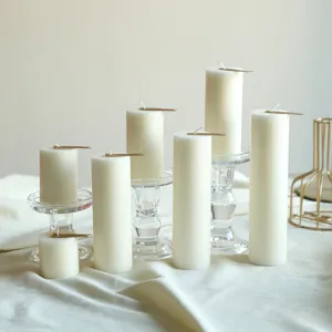 Candele profumate cilindriche bianche di varie altezze con supporti in vetro per decorare.