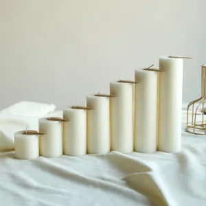 Set di candele profumate cilindriche bianche lisce, decorazioni minimaliste e accessori.