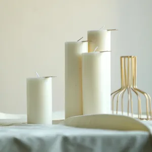 Primo piano di eleganti candele a pilastro bianche disposte ordinatamente per matrimoni e arredo.