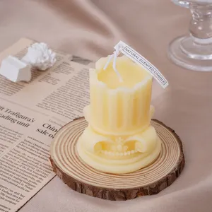 Primer plano detallado de una vela aromática de columna romana en un posavasos de madera.