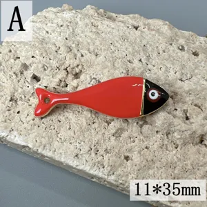 Nahaufnahme des roten Emailleschmucks in Goldrand, detailreiches DIY Fisch Anhanger Accessoire.