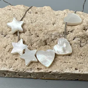 Detail de collier de perles en nacre etoile et coeur, accessoire de chaine argente.