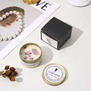 Scented candle in gold tin with dried flowers, natural soy wax, luxury gift box packaging, relaxing decor.