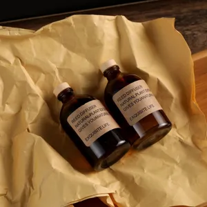 Set di flaconi per diffusore a bastoncini in vetro ambrato con tappi in legno ed etichette carta.