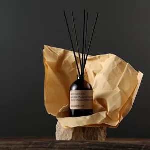 Bottiglia diffusore di fragranza in vetro con bastoncini neri e base in pietra per ambienti.