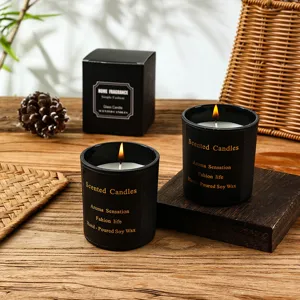 Detailed shot of black scented soy wax candle in glass jar with cozy wooden table setting.