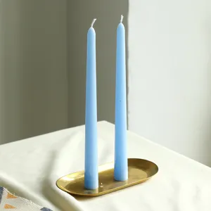 Gros plan détail de bougies parfumées coniques bleu clair sur plateau doré pour ambiance.