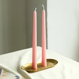 Bougies coniques roses sur plateau en laiton, détail de décoration minimaliste pour dîner romantique.