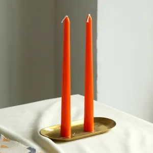 Bougies parfumées coniques orange avec plateau doré pour dîners romantiques et décoration.